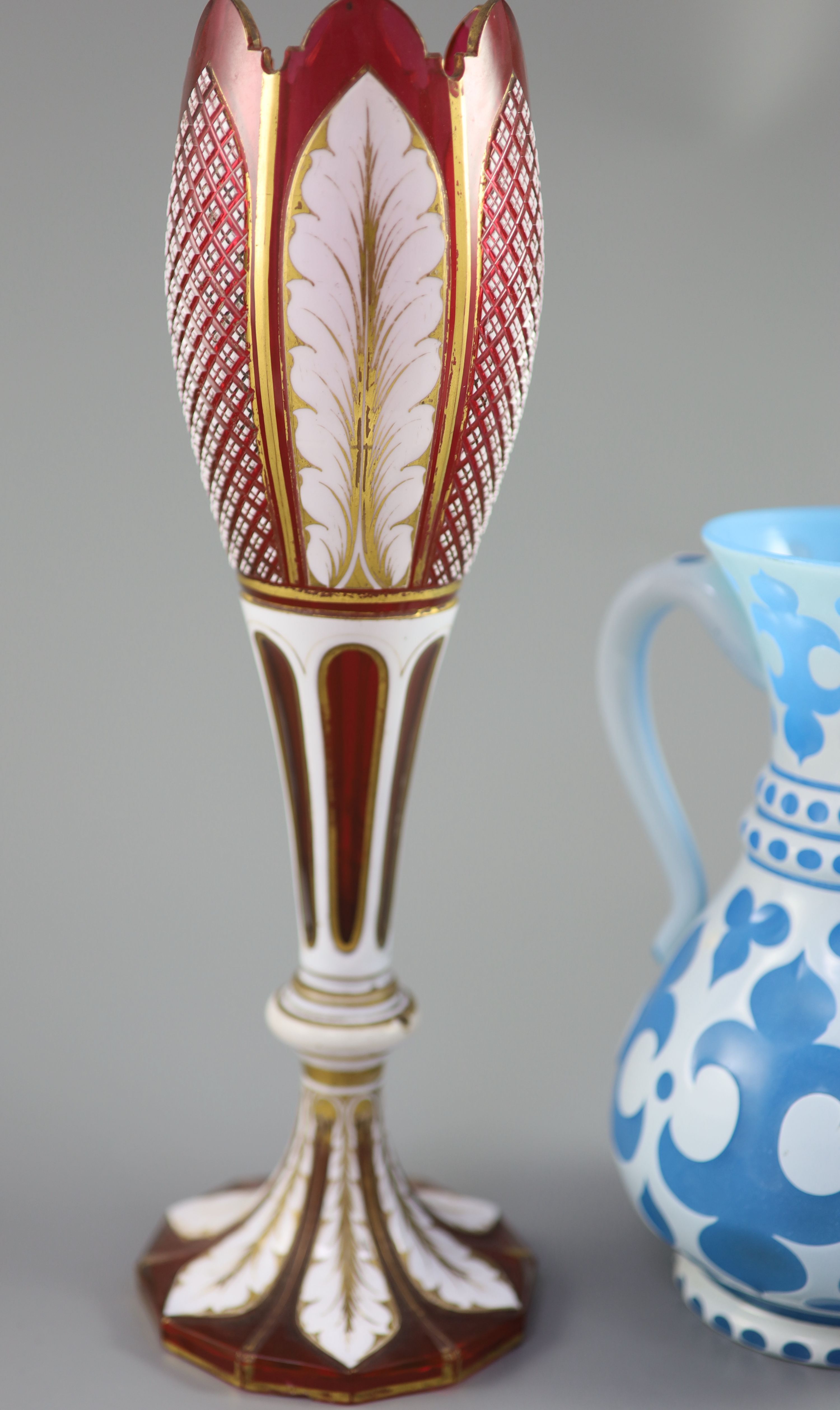 A Bohemian blue and white overlaid glass jug and a similar ruby and white overlaid glass vase, tallest 35cm